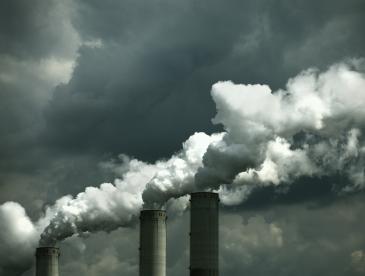 Smokestacks releasing emissions on a cloudy day.