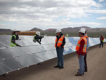 People in hard hats at a solar energy farm.