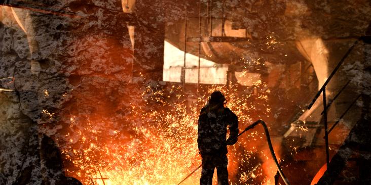 Steelworker working with very hot materials, amidst sparks.