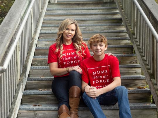 A mother and son sitting on steps wearing "Moms Clean Air Force" shirts.